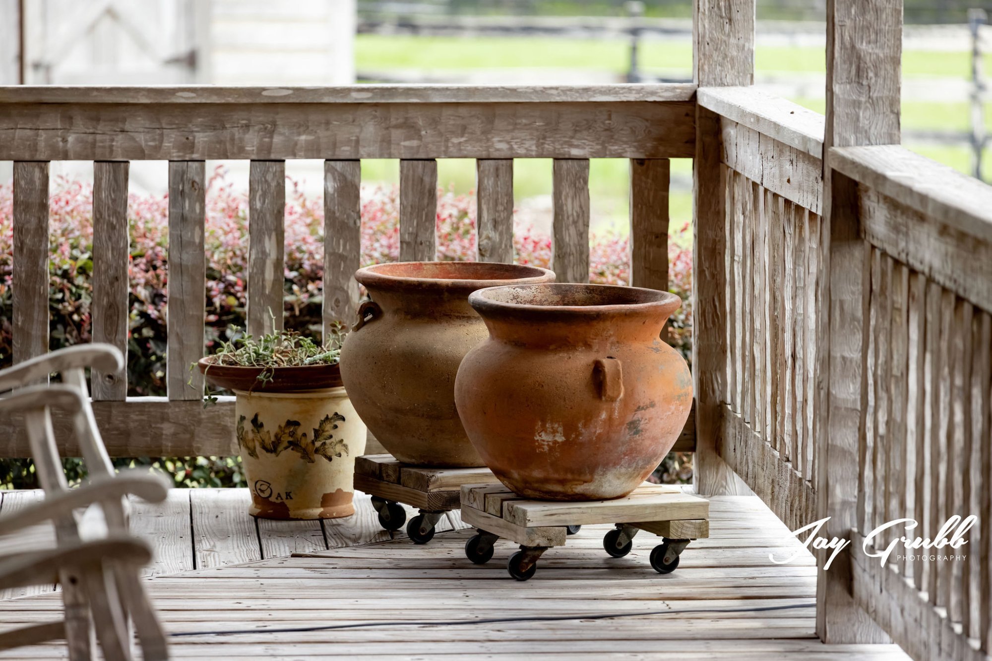 Weathered terracotta pots on the porch beside blooming shrubs