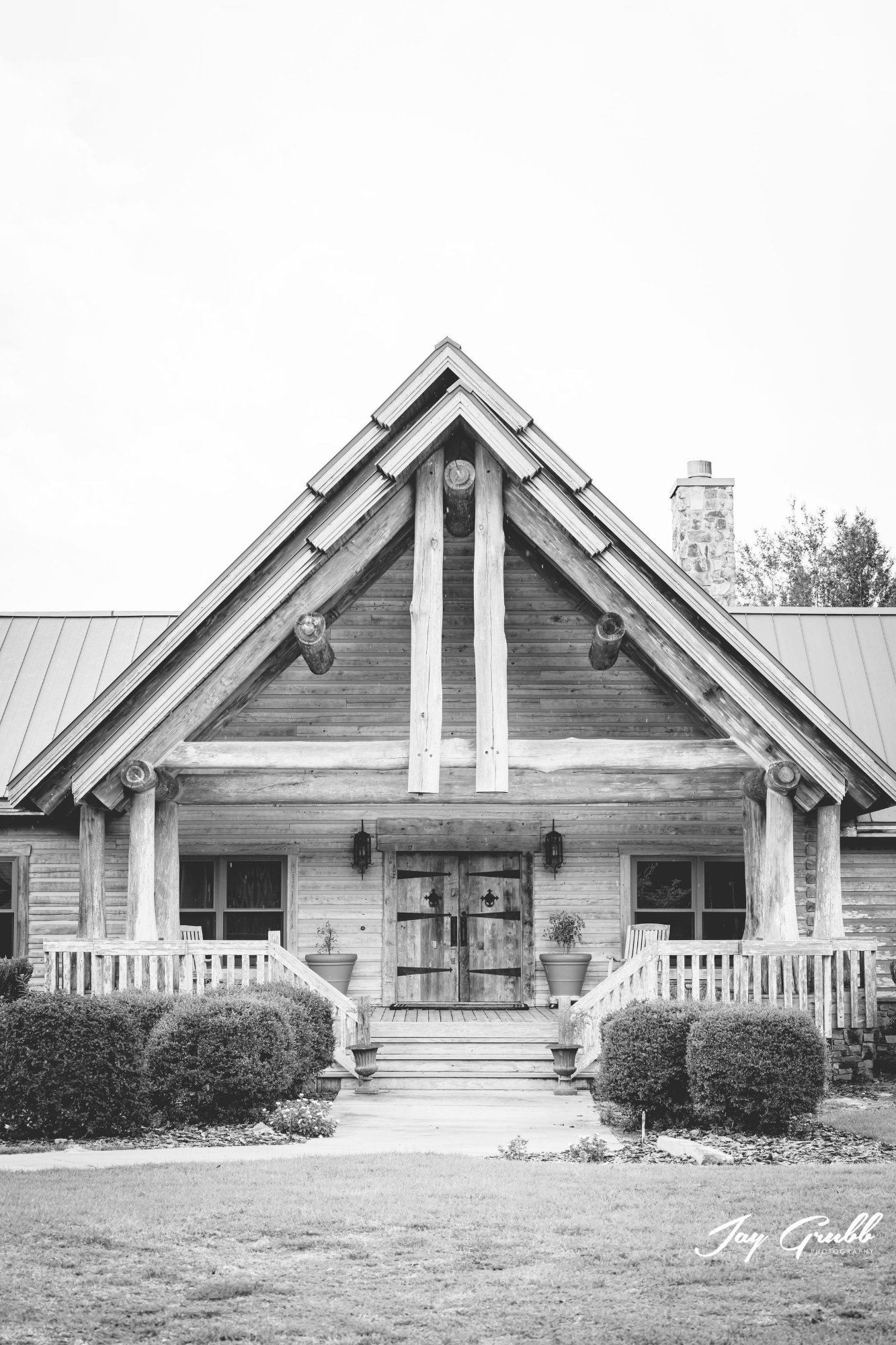 Black-and-white photograph of the front of the log ranch house with its dramatic gable